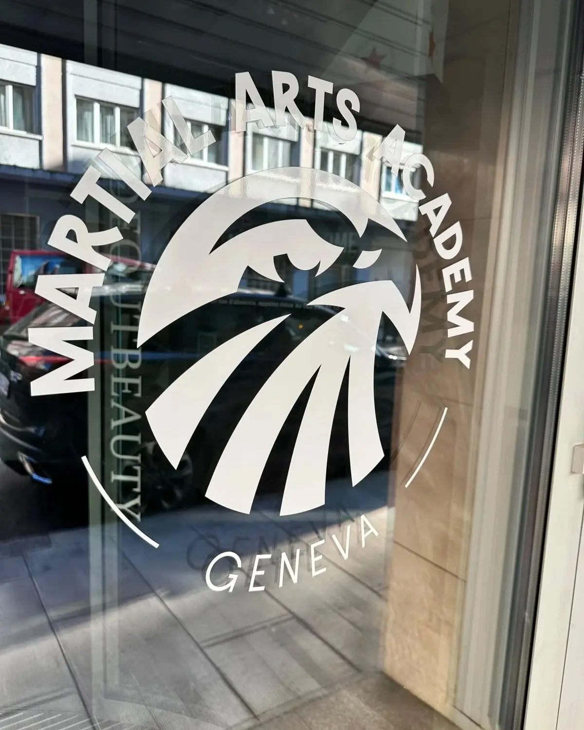 Logo de la Martial Arts Academy sur la vitre propre d'une salle de sport à Genève